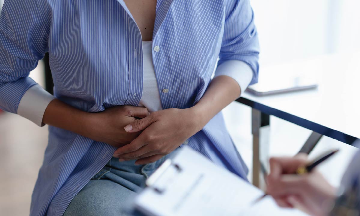 A person in a clinician's office is clutching their stomach.